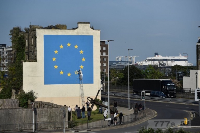 Новая картина художника Бэнкси показывает, как уборщик счищает одну из звезд на флаге Евросоюза.
