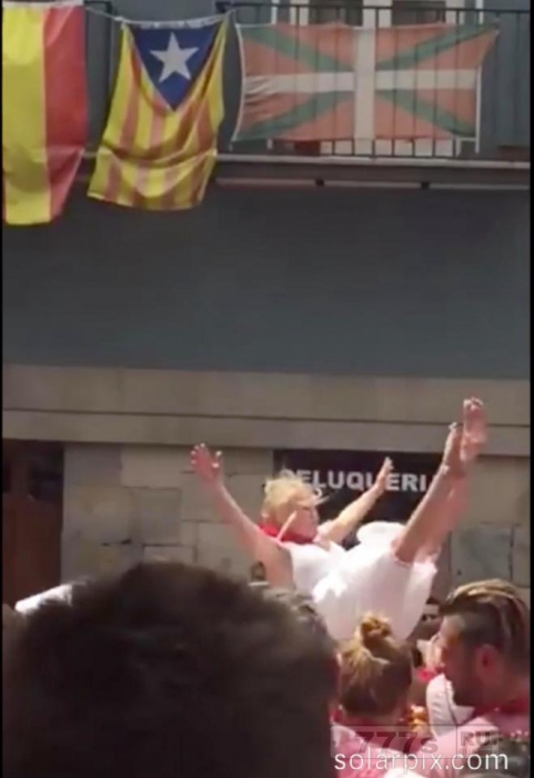 Девушка поднимается на фонтан города Памплона, распахивается и прыгает вниз в толпу поклонников на фестивале Сан-Фермин 2017.