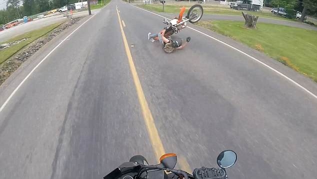 Мотоциклист скользит по дороге после того, как свалился с поднявшегося на дыбы мотоцикла