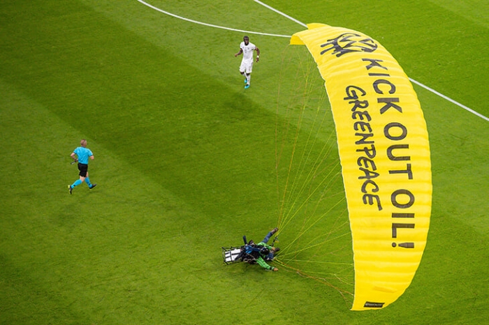 Много футбольных фанатов было госпитализировано, когда парашютист из Гринпис протестуя, приземлился на стадион во время матча